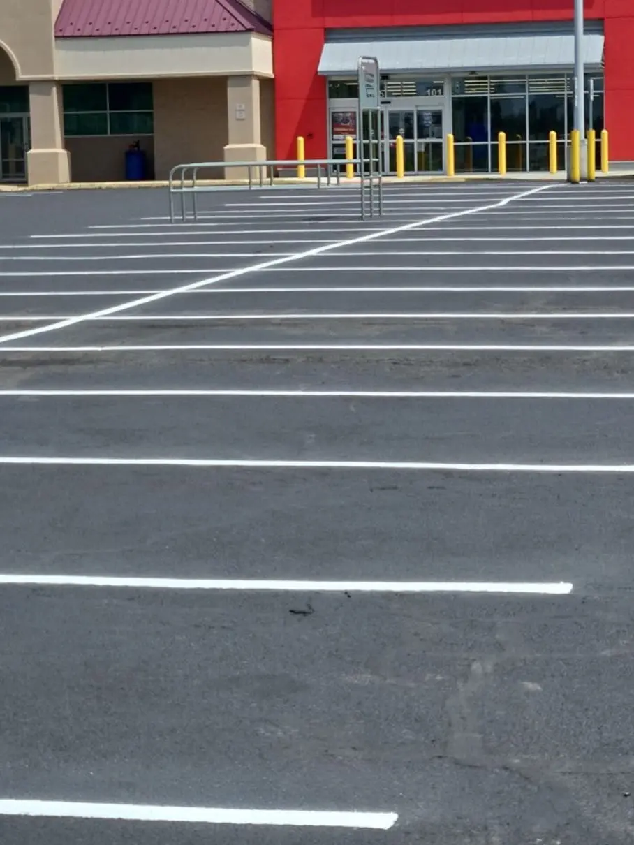 Crisp white parking stripes on a freshly sealcoated commercial lot in front of a red retail building